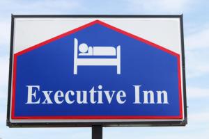 a sign for an excitability im with a bed at Executive Inn in Owatonna