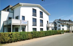 a white building with a balcony on a street at Amazing Apartment In Börgerende in Börgerende-Rethwisch