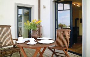 a wooden table with two chairs and a vase with flowers at Amazing Apartment In Börgerende in Börgerende-Rethwisch