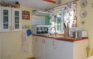 a kitchen with white cabinets and a sink and a window at Gorgeous Home In Sr With Kitchenette in Särö