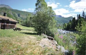 a picnic table next to a river next to a cabin at Holde in Hemsedal