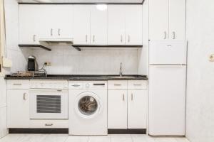 a kitchen with white cabinets and a washing machine at San Mames View Apartment in Bilbao