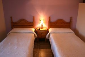 a bedroom with two beds and a lamp on a night stand at Alojamientos Plaza Mayor in Trujillo