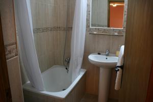 y baño con bañera, lavamanos y ducha. en Alojamientos Plaza Mayor, en Trujillo