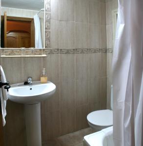 y baño con lavabo, aseo y espejo. en Alojamientos Plaza Mayor, en Trujillo