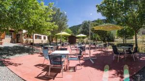 un patio con mesas, sillas y sombrillas en Cabañas de Javalambre, en Camarena de la Sierra