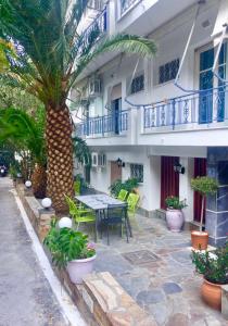 a patio with a table and a palm tree in front of a building at Hotel George in Agios Kirykos
