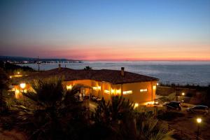 a house with lights in front of the ocean at night at Residence Pietre Bianche ApartHotel in Pizzo