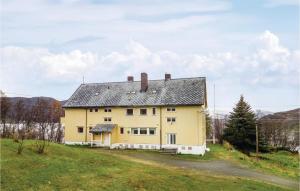 une grande maison jaune sur une colline herbeuse dans l'établissement Cozy Home In Korsfjorden With House A Mountain View, à Komagfjord