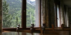 a room with a table and chairs and a large window at El Pradet in El Serrat