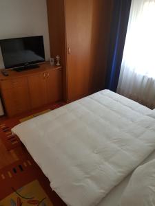 a bedroom with a large white bed and a flat screen tv at Apartament Melinda in Oradea