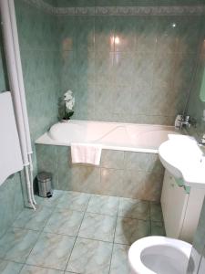 a bathroom with a tub and a toilet and a sink at Apartament Melinda in Oradea