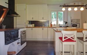 a kitchen with white cabinets and a red chair at Awesome Home In Kallinge With 2 Bedrooms in Möljeryd