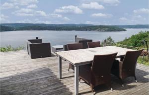 a table and chairs on a deck with a view of a lake at Awesome Home In Nordre Frogn With 3 Bedrooms And Wifi in Båtstø