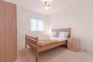 a bedroom with a wooden bed and a night stand at The Penthouse @ Waterside Grange in Slough
