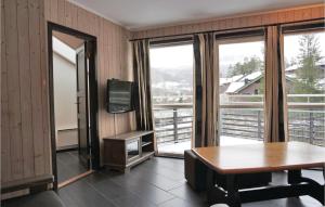 a room with a table and a tv and windows at 2 Bedroom Awesome Apartment In Hemsedal in Hemsedal