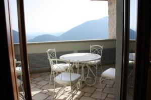 una mesa y sillas en un balcón con montañas en La Codarda country house, en Pescosolido