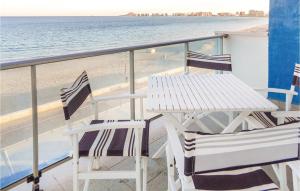 San Blas的住宿－Awesome Apartment In La Manga Del Mar Menor With Kitchenette，俯瞰海滩的阳台配有两把椅子和一张桌子