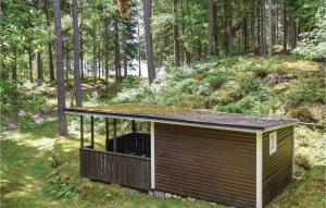 a small building with a roof in the woods at 3 Bedroom Nice Home In Hallaryd in Hallaryd
