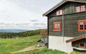 a wooden house with red windows on a green field at 9 Bedroom Awesome Home In Vinstra in Vinstra
