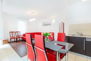 a kitchen and dining room with a table and red chairs at Apartamenty Morskie Oko by Renters in Międzyzdroje