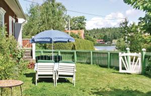 a table and chairs under an umbrella in a yard at Lovely Home In Eskilstuna With House Sea View in Sundby