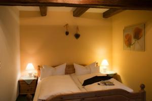 een slaapkamer met een bed met witte lakens en 2 lampen bij Hotel Schuberths am Markt in Buttenheim