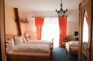 Schlafzimmer mit einem Bett und einem Fenster mit orangefarbenen Vorhängen in der Unterkunft Hotel Schuberths am Markt in Buttenheim