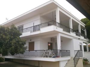 a white house with balconies and a tree at Kalaitzis Apartments in Kalivia Poligirou