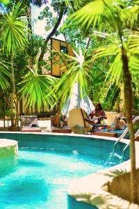 una piscina con palmeras y gente sentada en sillas en Bufo Alvarius, en Tulum