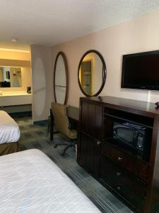 a hotel room with a bed and a desk with a television at Pepper Tree Inn in Beaverton