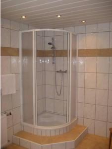 um chuveiro numa casa de banho em azulejo com uma porta de vidro em Pension Klausnerhof em Brixen im Thale