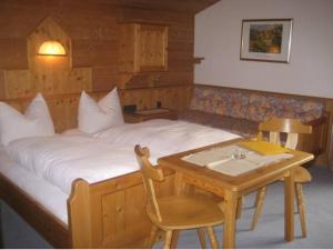 um quarto com uma cama e uma mesa de madeira em Pension Klausnerhof em Brixen im Thale