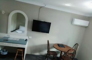 a room with a desk and a table and a tv at Excelsior Motor Inn in Port Macquarie