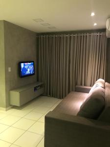 a living room with a couch and a flat screen tv at Apto ALTO PADRÃO em Maceió in Maceió