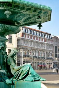 a green statue in front of a building at Hotel Avenida Palace in Lisbon