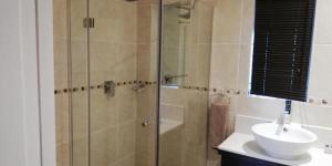 W łazience znajduje się szklana kabina prysznicowa i umywalka. w obiekcie Gold Crest Guesthouse w mieście Roodepoort