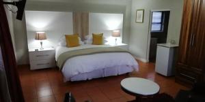 Gold Crest Guesthouse في روديبورت: غرفة نوم بسرير مع طاولتين ومصباحين