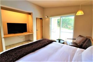 um quarto com uma cama grande e uma televisão em Villa Del Mar Nosoko em Ishigaki