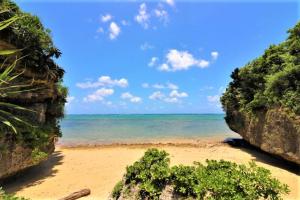 a view of a beach from between two rocks at Villa Del Mar Nosoko in Ishigaki Island