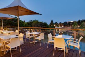 a deck with tables and chairs and an umbrella at ANEW Hotel Roodepoort Johannesburg in Roodepoort