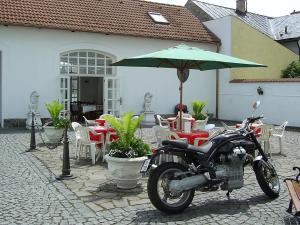 ホルニー・プラナーにあるPension Šejkoの傘付きテーブルの横に駐輪するオートバイ