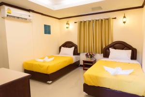 Habitación de hotel con 2 camas con sábanas amarillas en Honey House 3, en Jomtien Beach