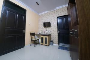 Habitación con puertas negras, escritorio y TV. en RedDoorz Syariah near RSUD Ainun Habibie Gorontalo, en Limboto