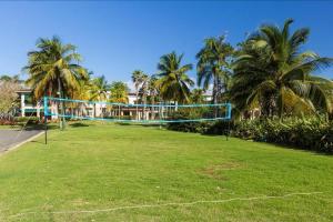 a volley ball net in a park with palm trees at Villa Iris 2 story ocean view villa w/ pool access in Vega Alta