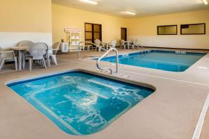 a pool in a hotel room with tables and chairs at Quality Inn & Suites Lenexa Kansas City in Lenexa