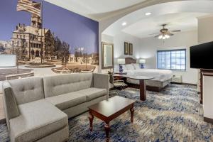 a large hotel room with a bed and a couch at Clarion Pointe Sulphur Springs in Sulphur Springs