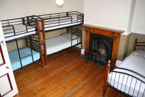 a room with three bunk beds and a fireplace at Arthouse Hostel in Launceston