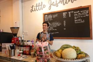 a man standing behind a counter with a table of food at Little Jasmine by the River in Phitsanulok