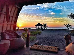 a sunset on a beach with a chair and an umbrella at Coconut Garden Beach Resort in Maumere